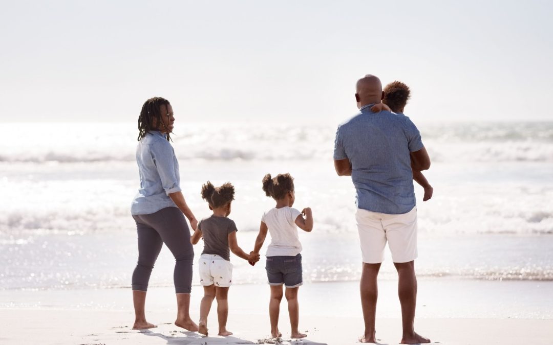 Family enjoying a tropical beach vacation in the Dominican Republic with turquoise Caribbean water, white sand, and palm trees.